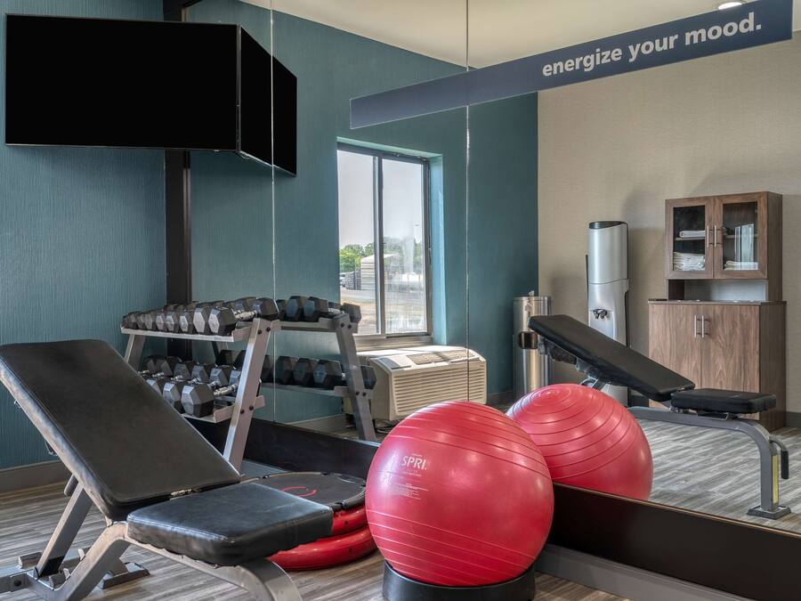 Un gimnasio con equipo de ejercicio, un televisor y un armario.
