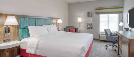 A modern hotel room with a large bed, a desk, and a chair.