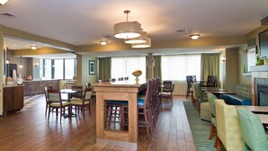 A spacious dining area with a central island, wooden chairs, and a patterned rug.
