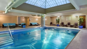 Ein Innenpool mit Oberlichter, einer Lounge mit Sitzgelegenheiten und einer Wanduhr.