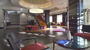 Eine geräumige Lobby mit Treppe, Sitzbereichen und einem großen Kronleuchter.