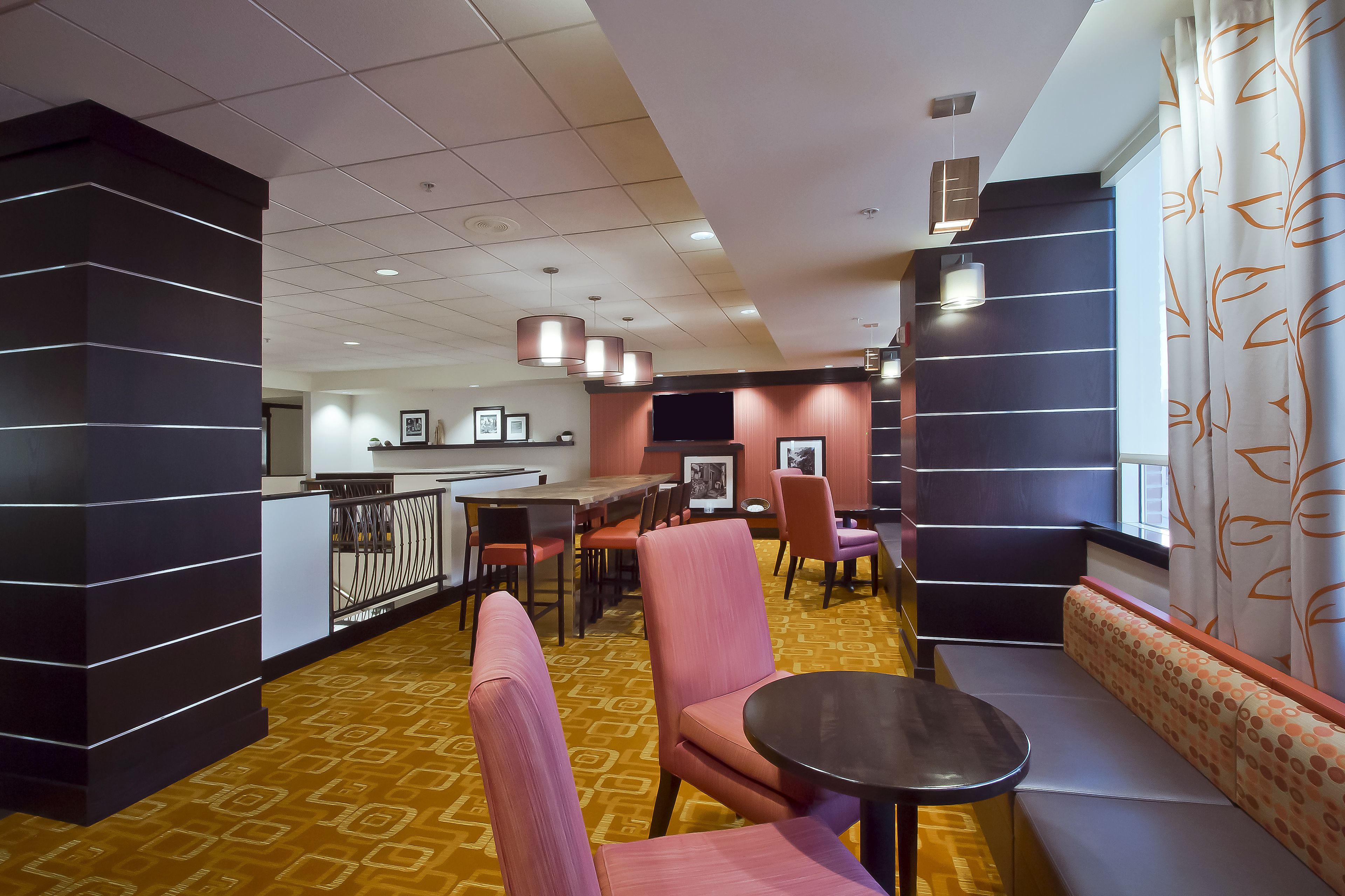 A hotel lobby with a bar area, seating, and a patterned carpet.
