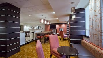 A hotel lobby with a bar area, seating, and a patterned carpet.