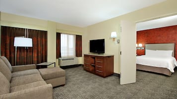 A hotel room with a sofa, a TV, a desk, and a bed.