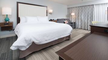 Ein Hotelzimmer mit einem großen Bett, einem Schreibtisch, einem Stuhl und einer Lampe.