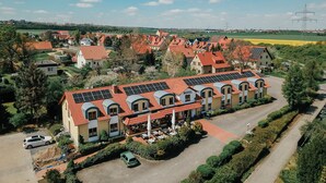 A hotel with a red-tiled roof, solar panels, and a parking area. - Landhotel Dresden (Dresden)