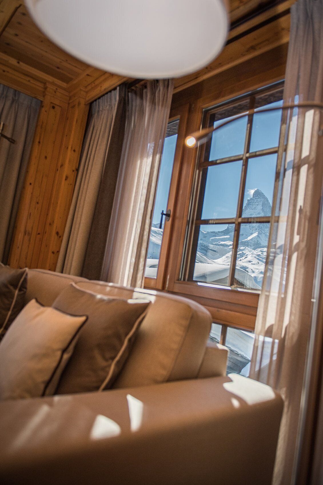 Ein gemütliches Blockhaus-Interieur mit einer Couch, Holzwänden und einem Fenster mit Blick auf die Berge.