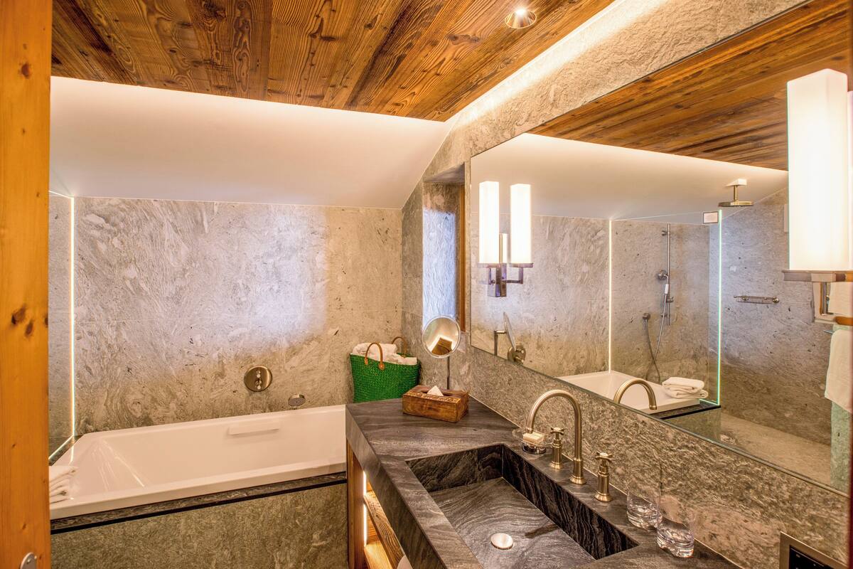 A modern bathroom with a bathtub, a double sink vanity, and a large mirror.
