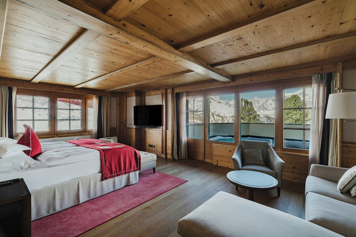 Une pièce de cabane en bois comprenant un lit, un téléviseur, une chaise et un canapé.