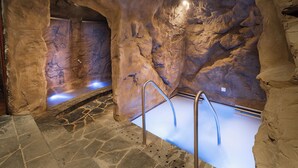 Ein Wellnessbereich mit Steinboden, Whirlpool und Metallleiter.