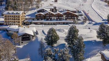 Un chalet enneigé comprenant plusieurs bâtiments, des pistes de ski et des arbres.