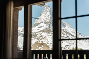 Vista pela janela de um pico montanhoso coberto de neve.