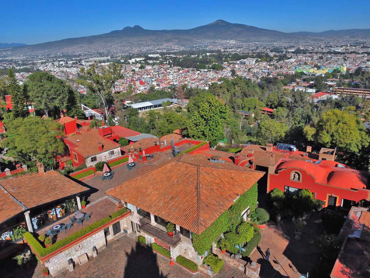 An aerial view of a town with red-roofed buildings, a prominent church, and a mountain in the background.