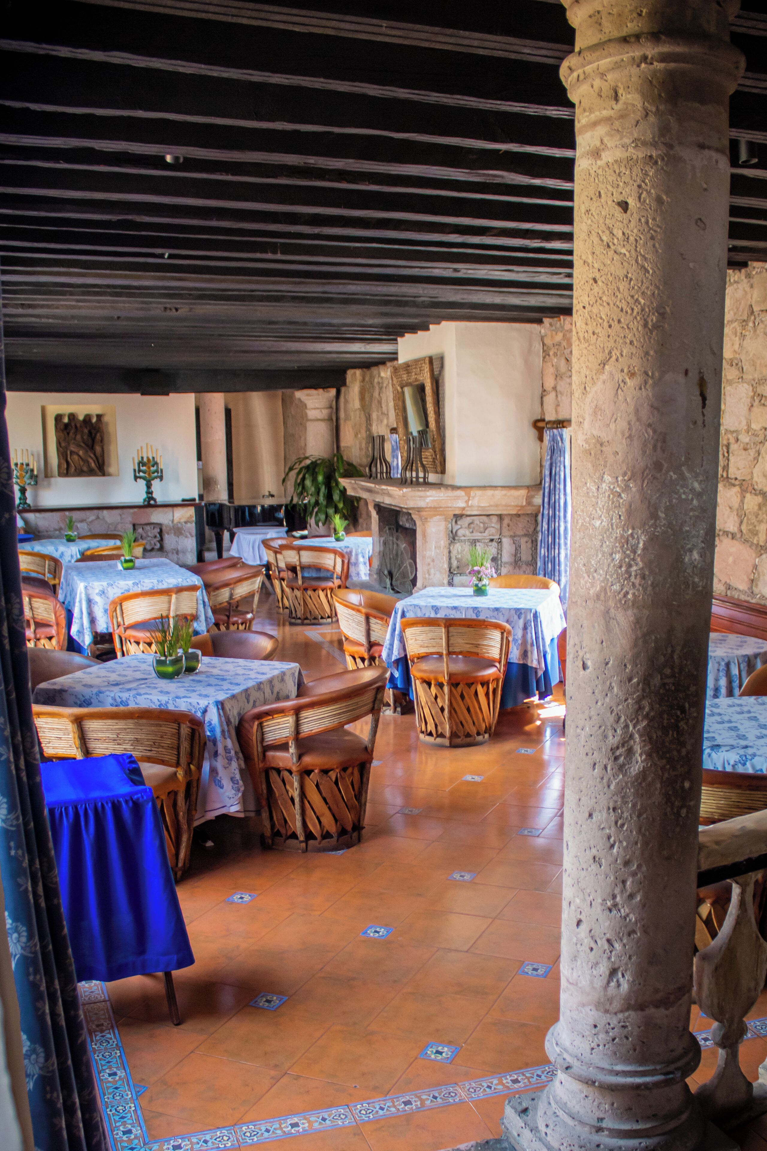 An indoor dining area with tables and chairs, a stone column, and a tiled floor.