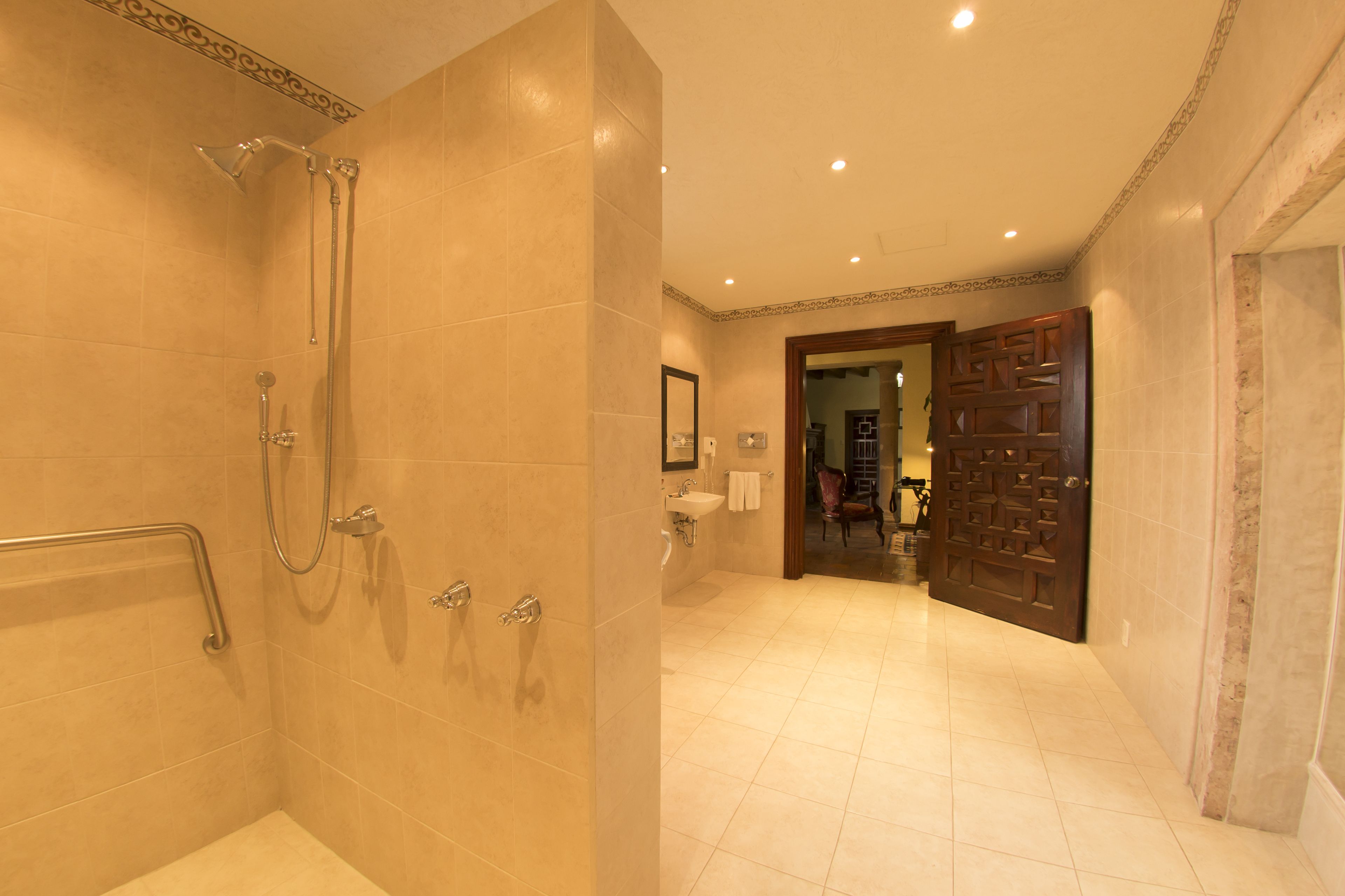 A spacious bathroom with a walk-in shower, grab bars, and a large mirror.