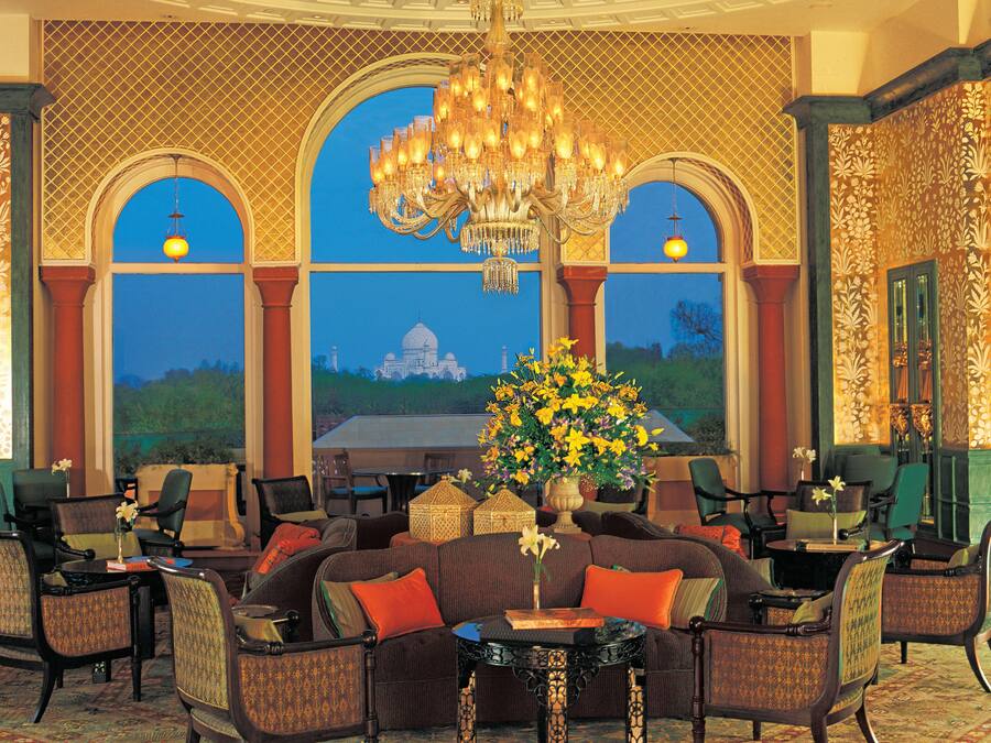 A luxurious lobby with a large chandelier, comfortable seating, and a view of a famous monument through arched windows.