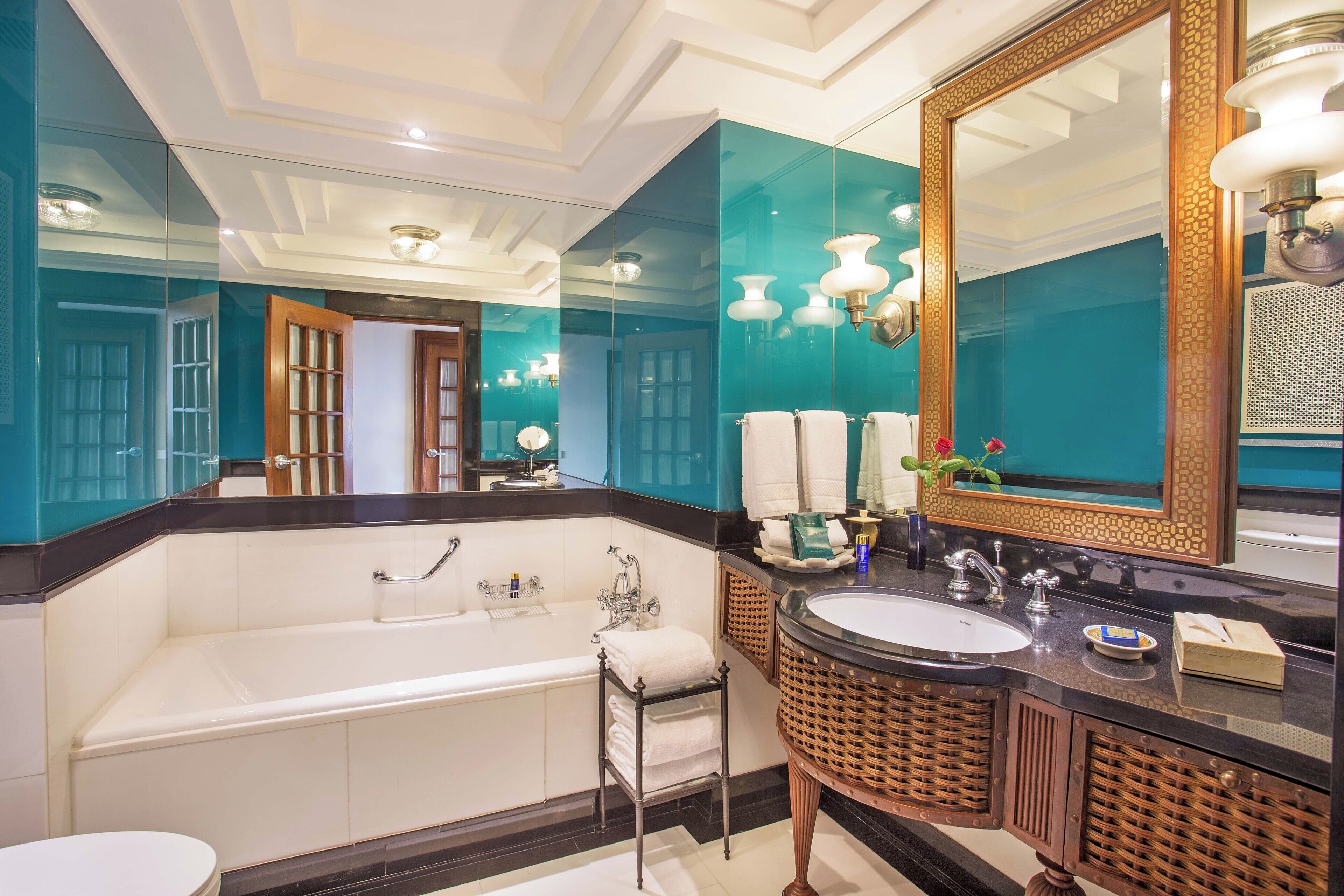 A modern bathroom with a large mirror, a bathtub, a sink, and a toilet.