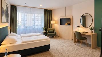 A hotel room with a bed, desk, chair, and a TV.