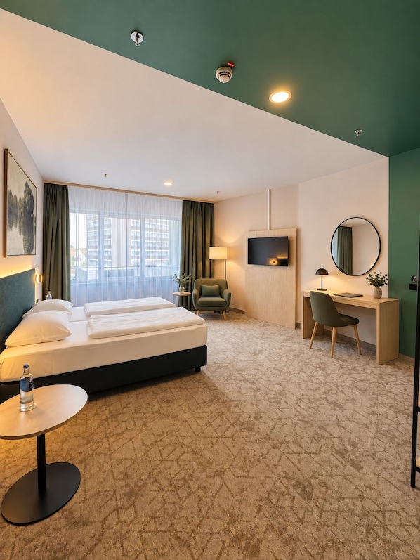 A hotel room with a bed, desk, chair, and a TV.