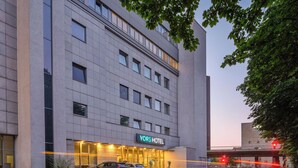 A modern hotel with a prominent entrance, large windows, and a visible parking area. - YORS Hotel Hannover (Hannover)