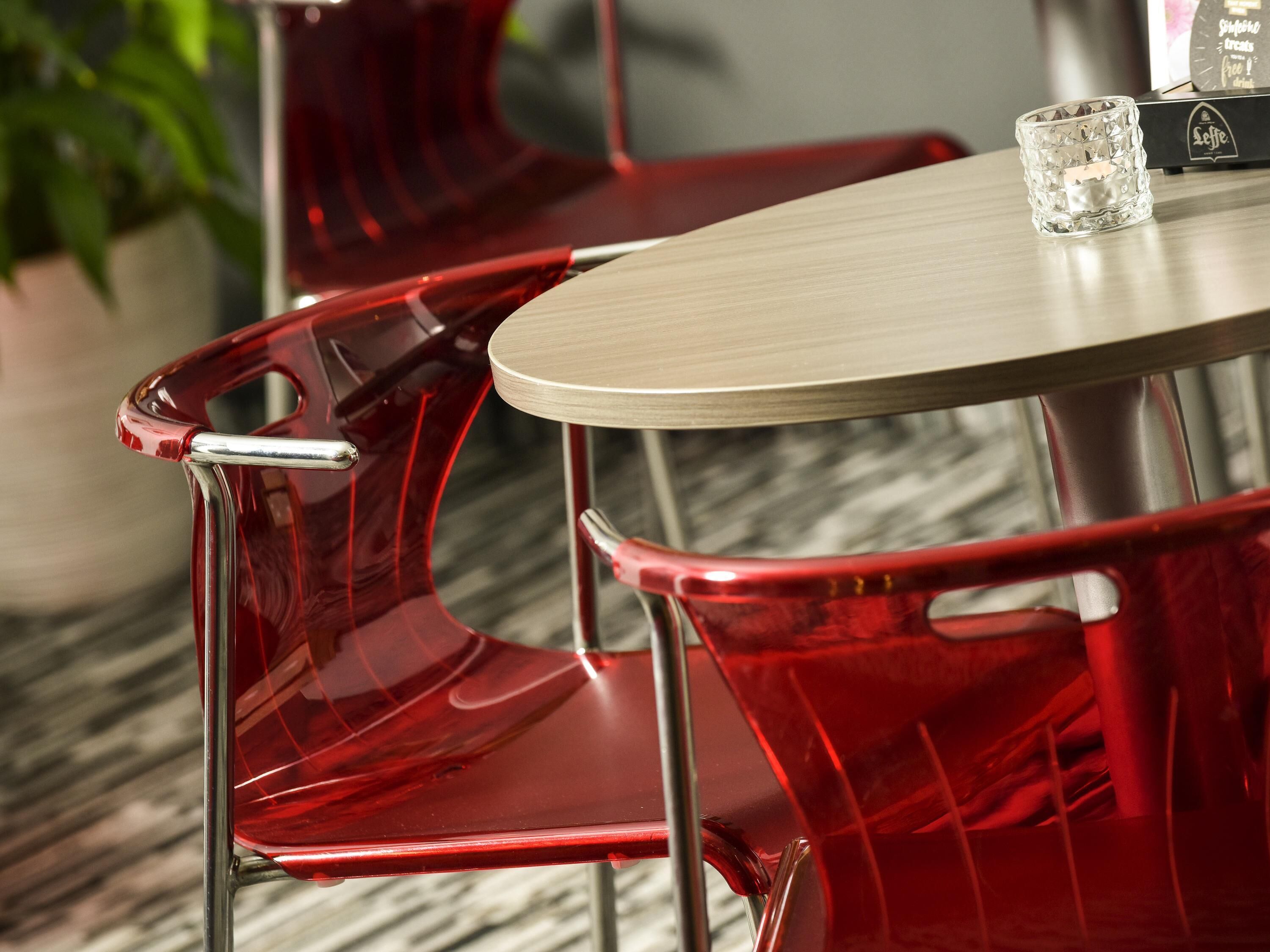 Un comedor moderno con una mesa redonda y sillas rojas.