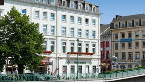 Ein weißes Gebäude mit einem Schild, das im Erdgeschoss „ibis HOTEL“ und „APOTHEKE“ zeigt.