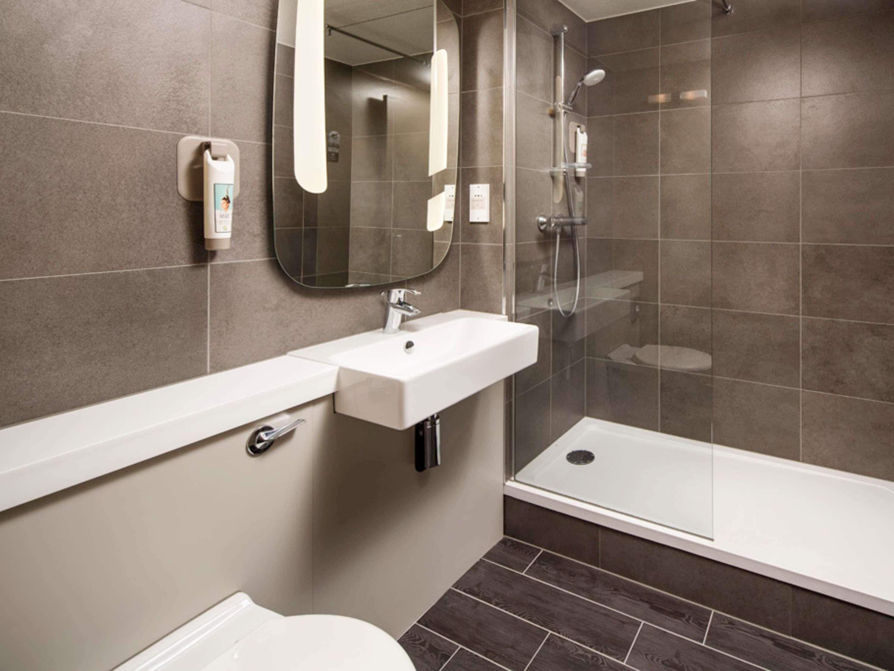A modern bathroom with a white sink, mirror, and shower.