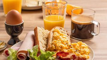 Un plat de petitdejuni amb ous, bacon i torrades, acompanyat de suc d'aranja i cafè.