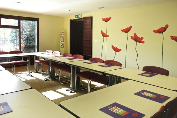A classroom with tables and chairs, a window with blinds, and a door with a sign. - ibis Coventry South (Coventry)