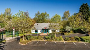A small building with a green door, surrounded by a parking lot and trees. - ibis Coventry South (Coventry)