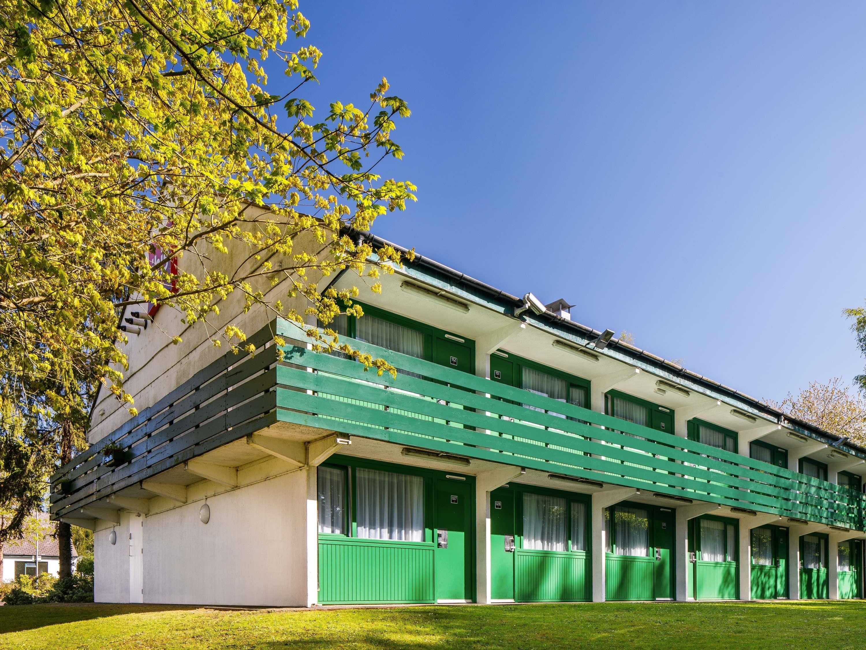 Een gebouw met een rij groene deuren, een plat dak en een gazon.