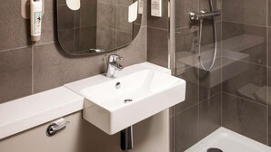 A modern bathroom with a white sink, a mirror, and a shower area. - ibis Coventry South (Coventry)