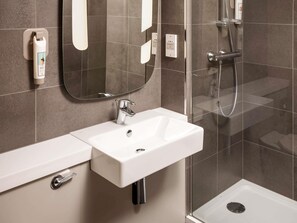 A modern bathroom with a white sink, a mirror, and a shower area. - ibis Coventry South (Coventry)
