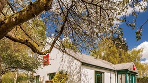 A white building with a green door and windows, surrounded by a well-maintained lawn and trees. - ibis Coventry South (Coventry)
