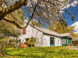 A white building with a green door and windows, surrounded by a well-maintained lawn and trees. - ibis Coventry South (Coventry)