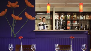 A restaurant with a bar area, tables with wine glasses, and a bartender. - ibis Coventry South (Coventry)