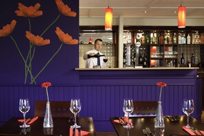 A restaurant with a bar area, tables with wine glasses, and a bartender. - ibis Coventry South (Coventry)