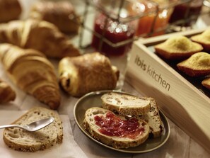 A breakfast buffet with various breads and pastries, including croissants and sliced bread with jam. - ibis Coventry Centre (Coventry)