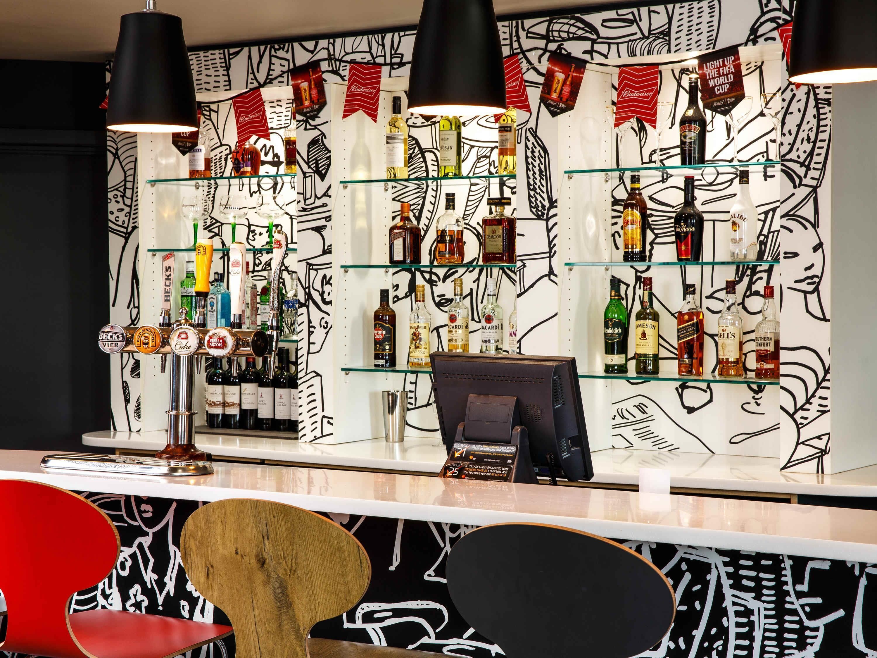 A bar area with multiple shelves of liquor bottles, a cash register, and a counter.