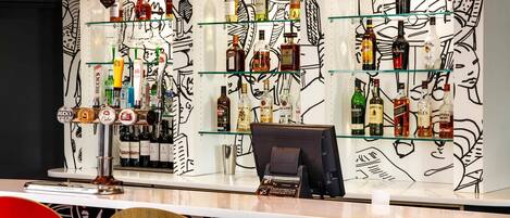 A bar area with multiple shelves of liquor bottles, a cash register, and a counter.