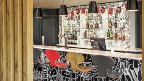 A bar area with a counter, black pendant lights, and a wall with a black and white abstract design. - ibis Coventry Centre (Coventry)
