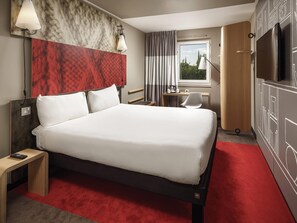 A hotel room with a large bed, bedside tables, a desk, a chair, a TV, and a window with curtains. - ibis Coventry Centre (Coventry)