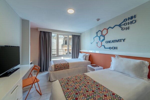 A hotel room with two beds, a desk with a TV, a chair, and a window with curtains.