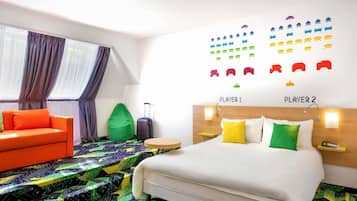 A hotel room with a bed, a sofa, a suitcase, and a wall with game icons.