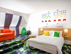 A hotel room with a bed, a sofa, a suitcase, and a wall with game icons.