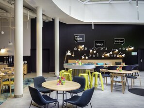 A modern interior with round tables, blue chairs, and a central bar area with neon signs.