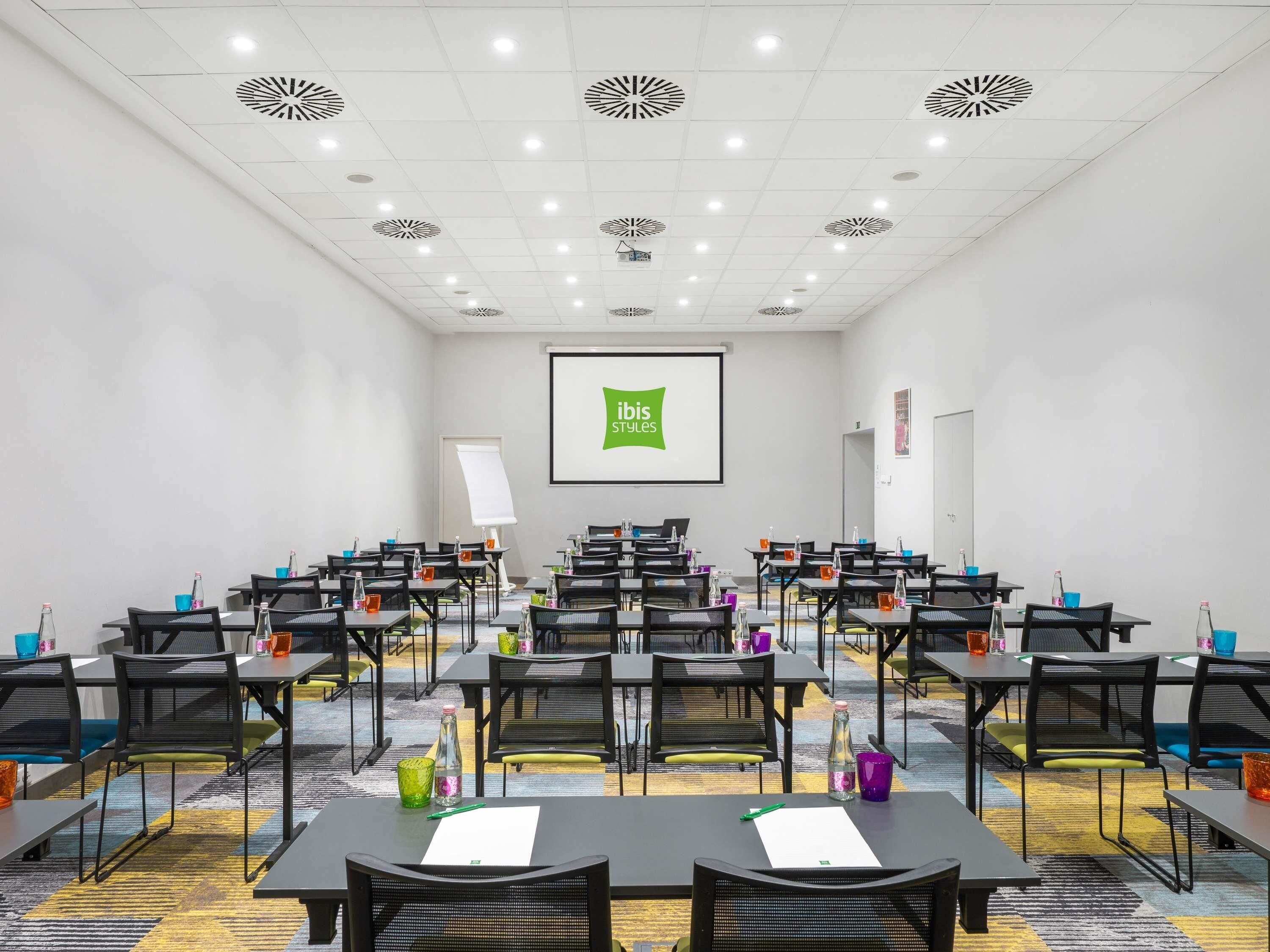 A conference room with tables and chairs, a projector screen, and a whiteboard.