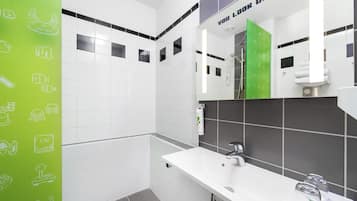 Un baño moderno con azulejos blancos y grises, un espejo grande, una ducha y un lavabo blanco con grifo.