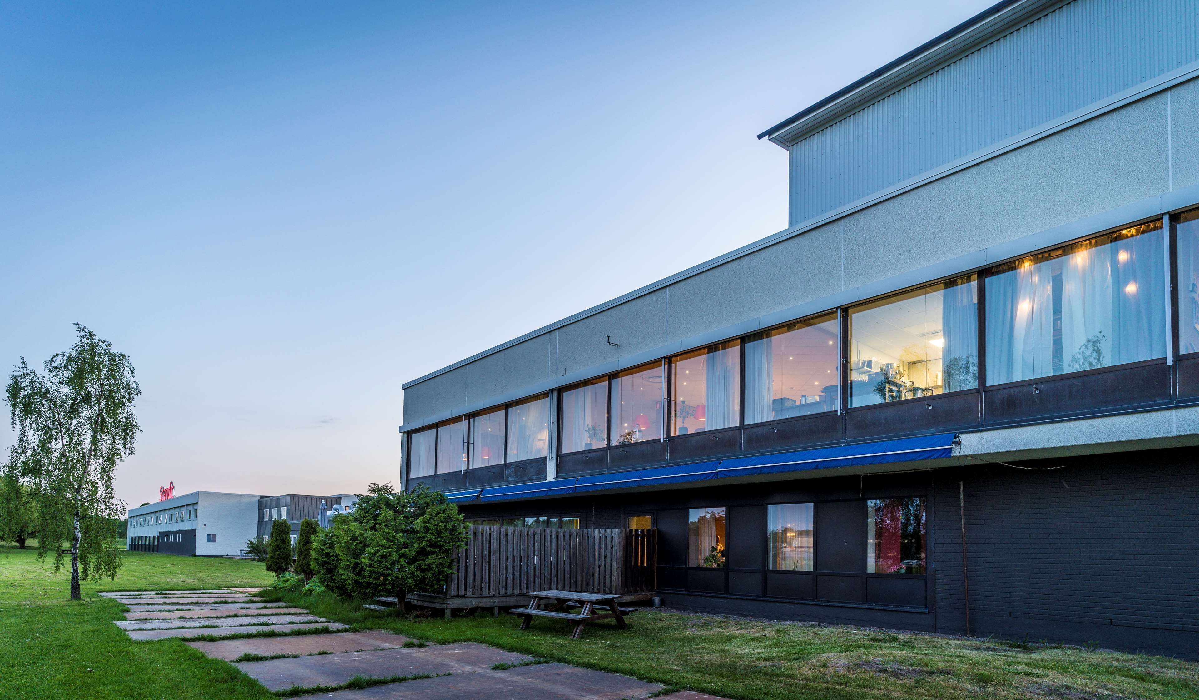 Ein modernes Gebäude mit großen Fenstern, einem flachen Dach und einer blauen Markise.
