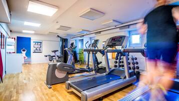 A gym with treadmills, elliptical machines, and a weight bench.
